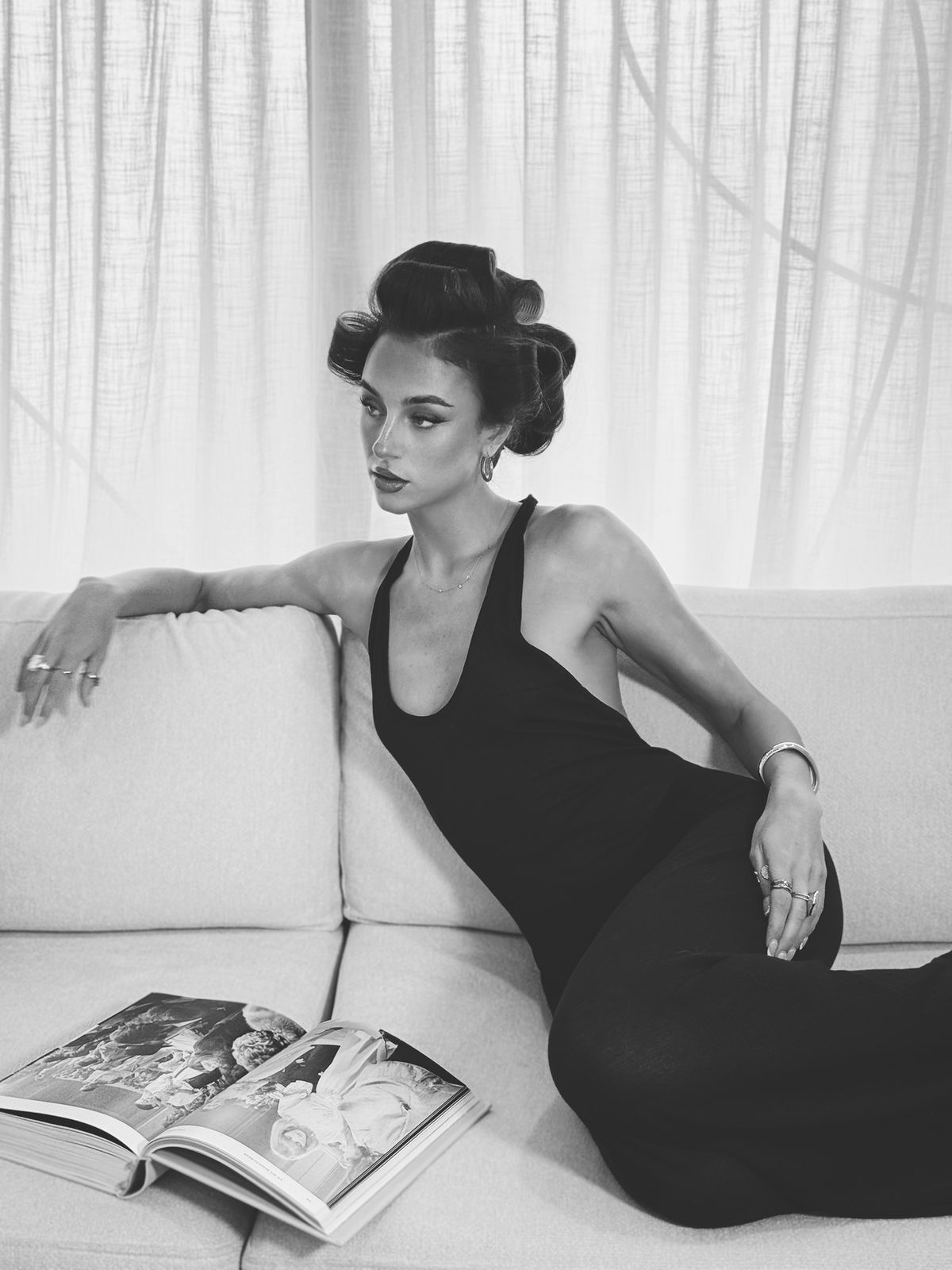 Editorial black and white portrait, model in rollers reclining on a sofa